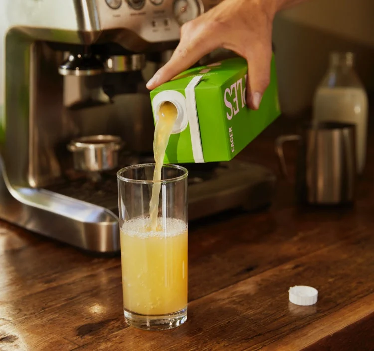 Warm kitchen scene pouring juice from an Eager carton
